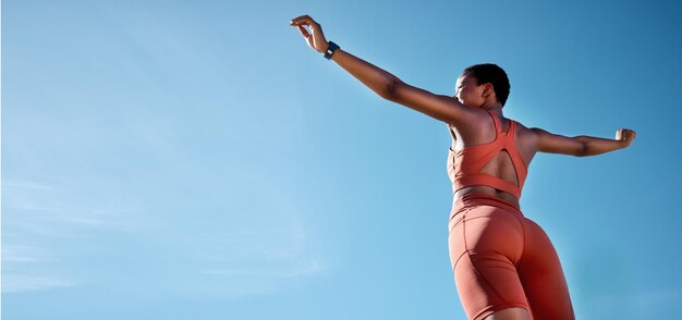 Braços de mulher para cima ou sucesso de fitness no fundo do céu azul em treinamento de treino ou metas de exercício para saúde ou bem-estar cardiovascular Atleta de esportes de corredor de baixo ângulo ou mãos levantadas com maquete