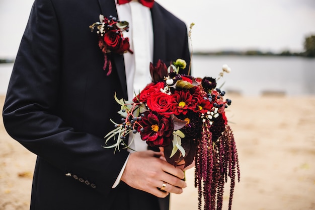 Bräutigam hält einen Hochzeitsstrauß von Blumen in der Hand