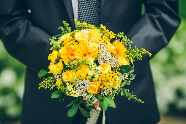 Bräutigam hält einen Strauß Sonnenblumen und Rosen ohne Gesicht