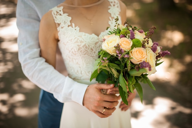 Bräutigam im weißen Hemd, das Braut im schönen Hochzeitskleid von der Rückseite umarmt