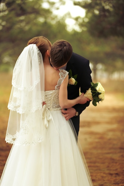 Foto bräutigam küsst braut auf einem wald
