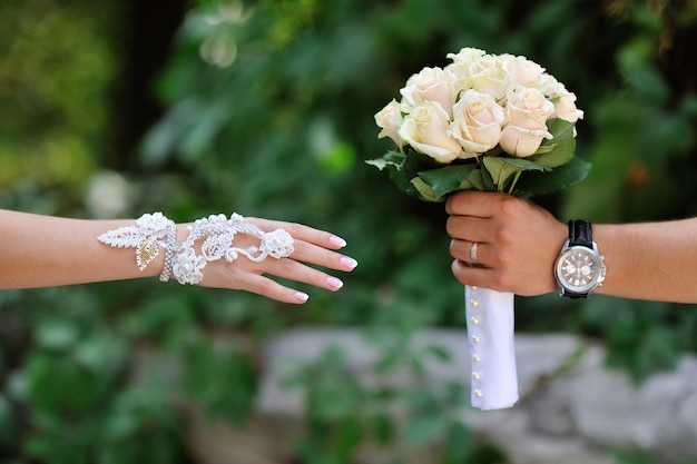 Bräutigam überträgt Braut Hochzeitsstrauß aus weißen Rosen