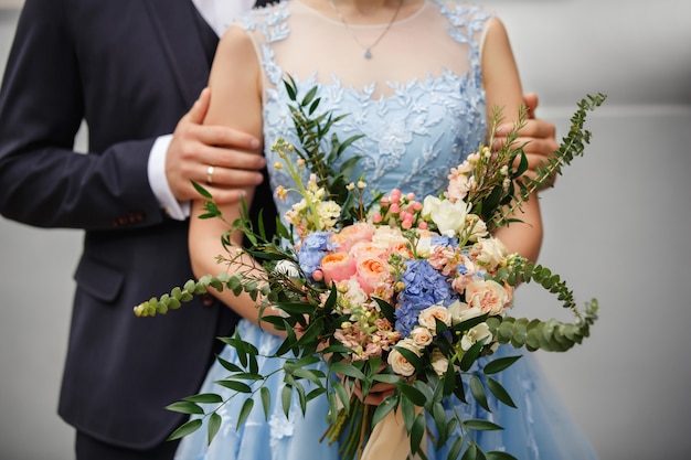 Bräutigam und Braut mit Hochzeitsstrauß von frischen Blumen