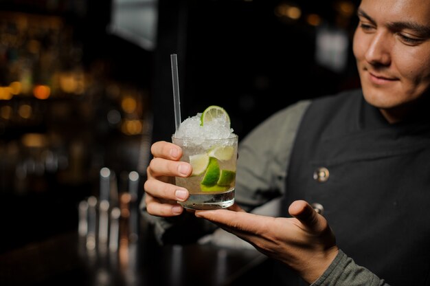 Braga sorridente segurando um copo cheio de caipirinha cocktail com um canudo