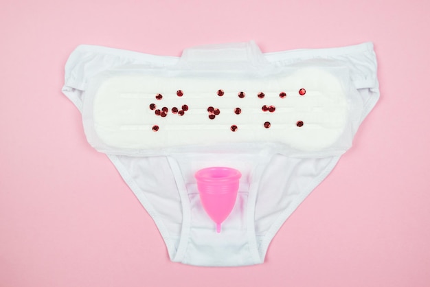 Bragas almohadillas copa menstrual sobre un fondo rosa El concepto de los períodos de las mujeres