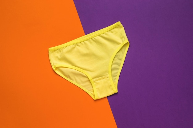 Bragas de mujer de color amarillo claro sobre un fondo naranja y morado Ropa interior de mujer Lay Flat