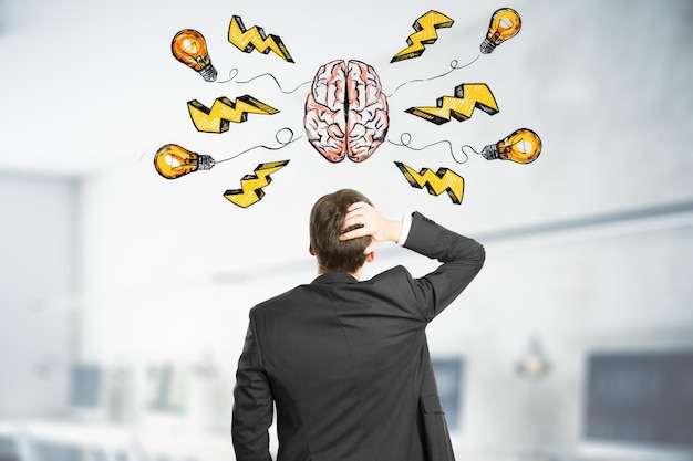 Brainstorming-Konzept mit nachdenklichem Geschäftsmann greift seinen Kopf und schaut auf einen transparenten Bildschirm mit handgeschriebener Skizze des menschlichen Gehirns und gelben Blitzschlag-Symbolen und Glühbirne