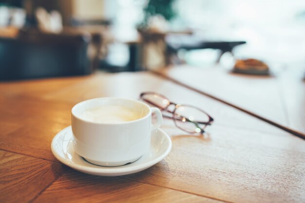 Branco de café e copos na mesa perto da janela