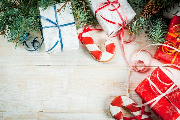 Branco de madeira festivo de Natal, com galhos de árvores de Natal, pinhas, decorações, presentes de Natal e pão de mel, vista superior