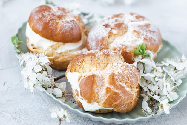 Brandbrötchen mit Schlagsahne und Puderzucker darauf Brandteigdessert Französische Windbeutel