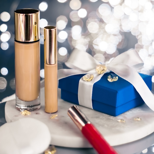 Branding cosmético glitter de natal e feminino blog conceito feriado maquiagem base corretivo e caixa de presente azul cosméticos de luxo presentes e produtos com etiqueta em branco para design de marcas de beleza