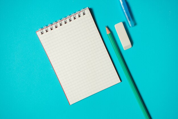 Branding-Modell mit Stift, Bleistift, Radiergummi und kleinem Notizbuch lokalisiert auf blauem Hintergrund. Speicherplatz kopieren. Draufsicht. Isometrisches Konzept. Schulmaterial