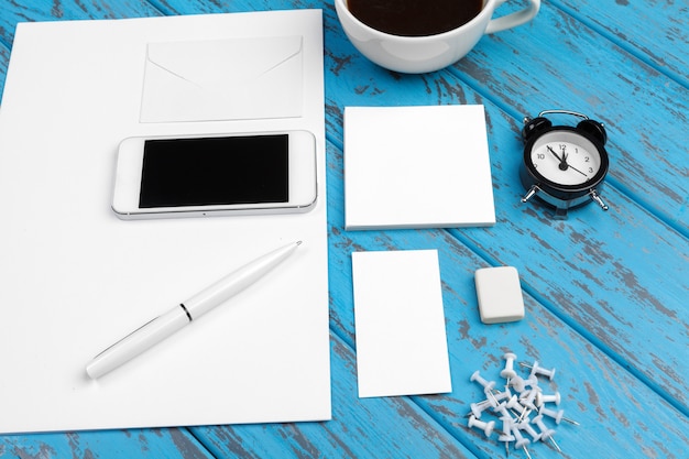 Branding papelería maqueta en el escritorio azul. vista superior de papel, tarjeta de visita, libreta, bolígrafos y café.