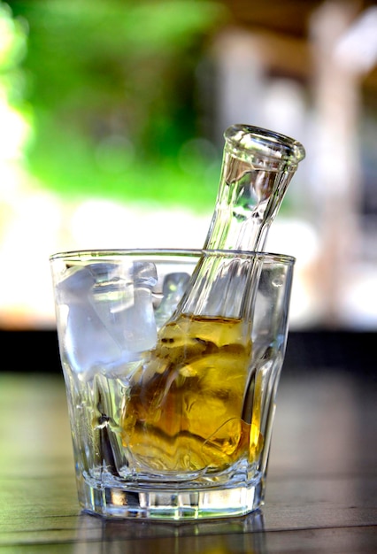 brandy de uva amarillo o zolta rakia en una pequeña botella de vidrio en vidrio con hielo famosa bebida alcohólica de Macedonia