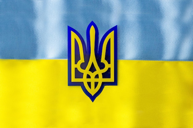 Brasão de armas da Ucrânia no fundo da bandeira Bandeira de listras azuis e amarelas