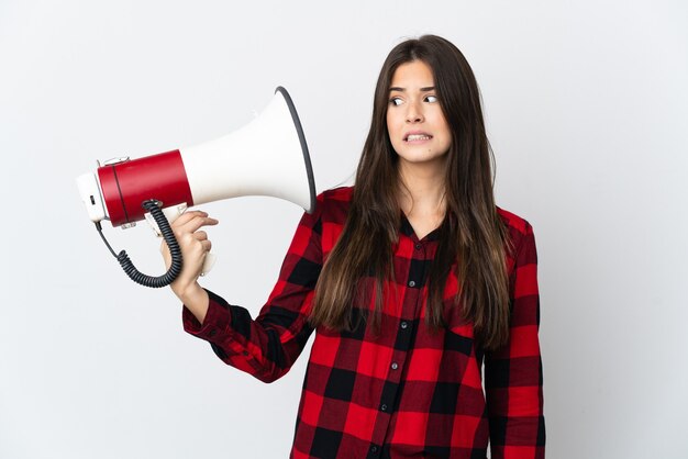 Foto brasileira adolescente isolada no branco segurando um megafone com expressão estressada