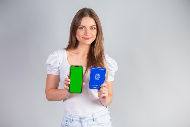 Brasileira loira segurando Carteira Nacional de Trabalho e Previdência Social e smartphone Tradução em Inglês Carteira de Trabalho e Previdência Social