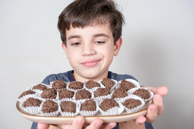 Brasileiro de 9 anos olhando para uma bandeja com várias bolinhas brasileiras e fazendo cara de decepção