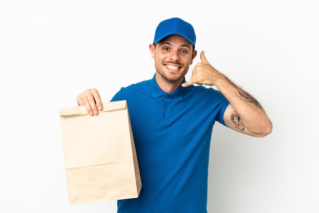 Brasileiro levando uma sacola de comida para viagem isolada no fundo branco, fazendo gesto de telefone. ligue-me de volta sinal