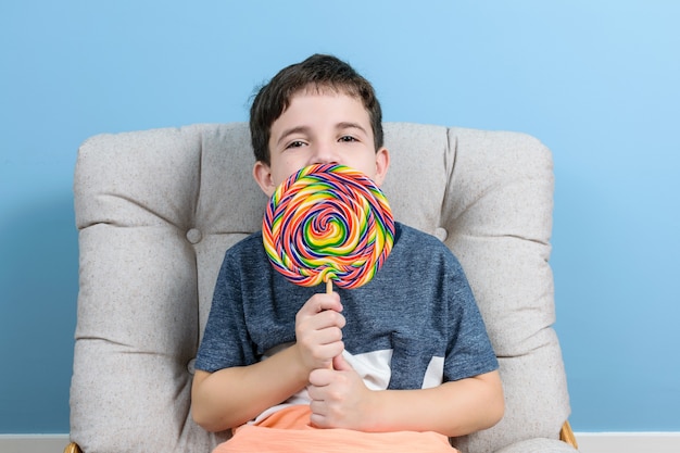 Brasileña de 8 años con una gran paleta coloreada y sentada en el sillón.