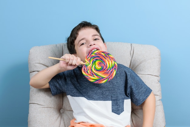 Brasileña de 8 años sentada en el sillón. Sosteniendo y listo para morder una piruleta.