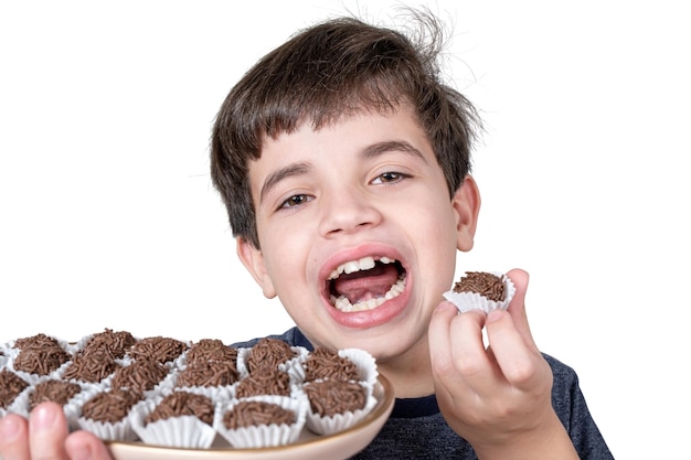 Brasileño de 9 años sosteniendo una bandeja con varias bolas de chocolate brasileño y con la boca abierta