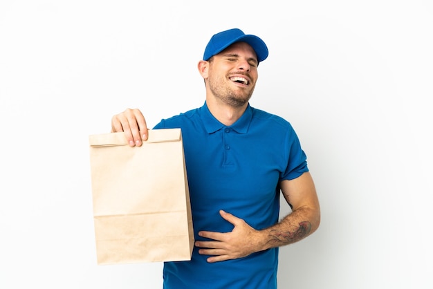 Brasileño tomando una bolsa de comida para llevar aislado sobre fondo blanco sonriendo mucho