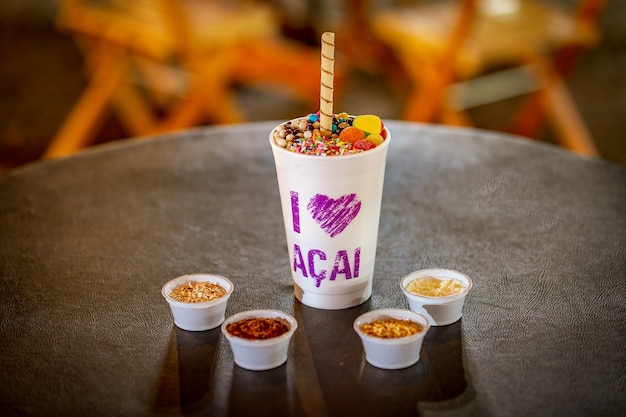 Brasilianische Acai eingefroren in einem Styroporbecher mit Kondensmilch und Bonbons Für Acai-Liebhaber