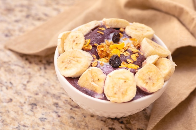 Brasilianische Acai in der Schüssel mit Bananenmüsli und Kondensmilch