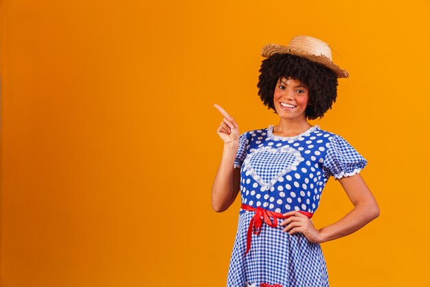 Brasilianische Afrofrau, die typische Kleidung für die Festa Junina auf Gelb trägt