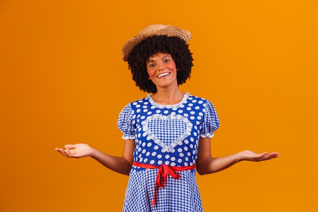 Brasilianische Afrofrau, die typische Kleidung für die Festa Junina auf Gelb trägt