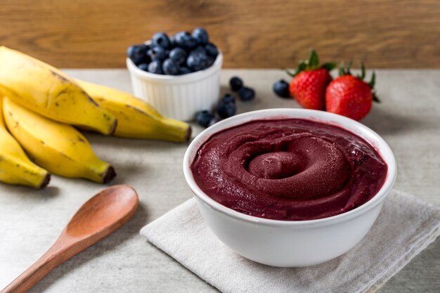 Brasilianische Eisschale mit gefrorenem und Acai-Beeren. mit Früchten auf hölzernem Hintergrund. Sommermenü Vorderansicht.