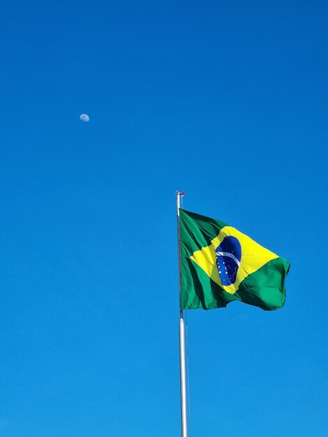 Foto brasilianische flagge mit mond und blauem himmel