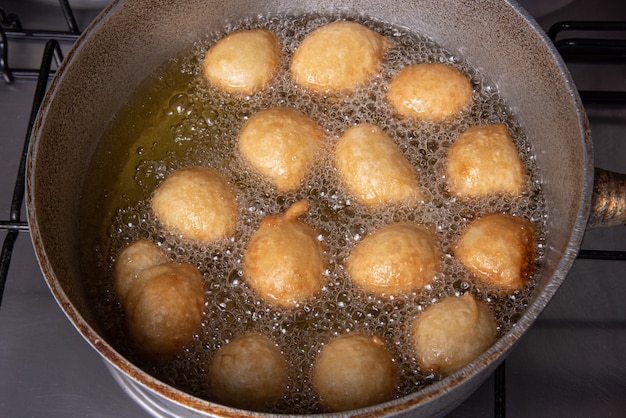 Brasilianische Süßigkeit namens Bolinho de Chuva, gebraten in einer Pfanne mit Öl, selektiver Fokus.