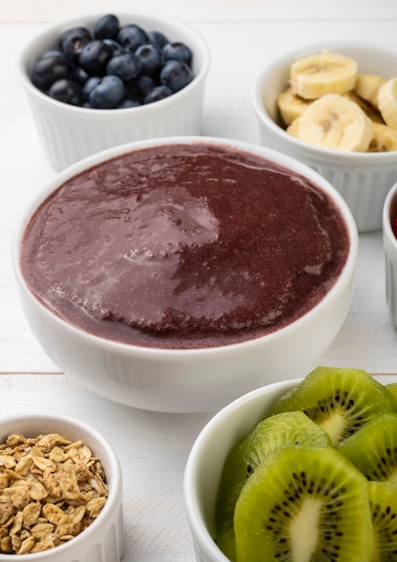 Brasilianische typische Acai-Schüssel mit Früchten und Müsli über Holzhintergrund.