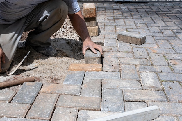 Brasilianischer Bauarbeiter, der Betonblock auf dem Boden platziert und nivelliert