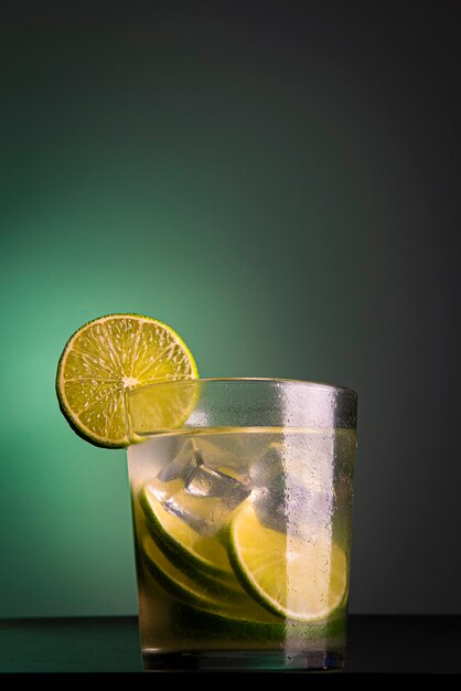 Brasilianischer Cocktail namens Caipirinha. Mit Zitrone, Eis und Cachaça auf dunklem Hintergrund mit grünen Lichtern. Platz kopieren