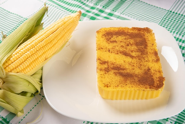 Brasilianischer Cural-Süßigkeitsmais und -mais arrangiert auf einem Tisch mit einem selektiven Fokus des dunklen Hintergrundes der grünen und weißen Tischdecke