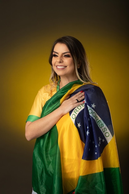 Brasilianischer Fan Brasilianischer Frauenfan, der im Fußball- oder Fußballspiel auf gelbem Hintergrund feiert Brasilien-Farben