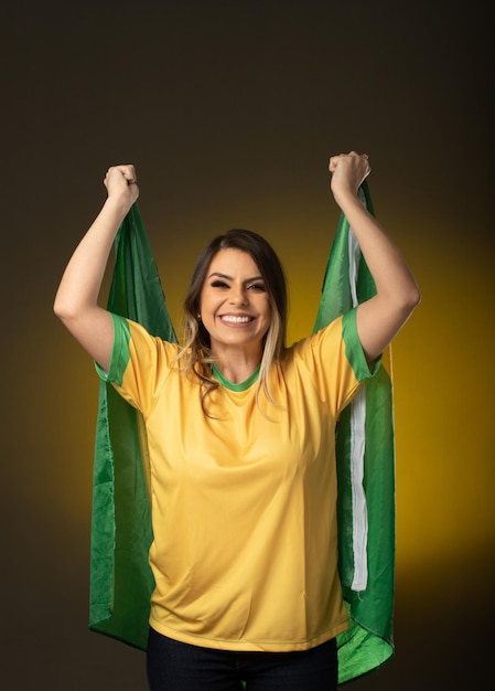 Foto brasilianischer fan brasilianischer frauenfan, der im fußball- oder fußballspiel auf gelbem hintergrund feiert brasilien-farben