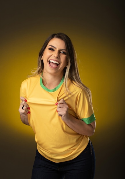 Brasilianischer Fan Brasilianischer Frauenfan, der im Fußball- oder Fußballspiel auf gelbem Hintergrund feiert Brasilien-Farben