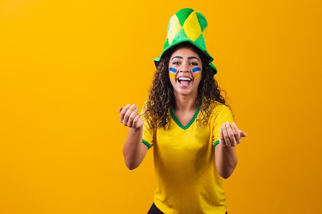 Brasilianischer Fan. mit Farbe als Make-up, brasilianischer Fan, der Fußball- oder Fußballspiel auf gelbem Hintergrund feiert. Farben Brasiliens.