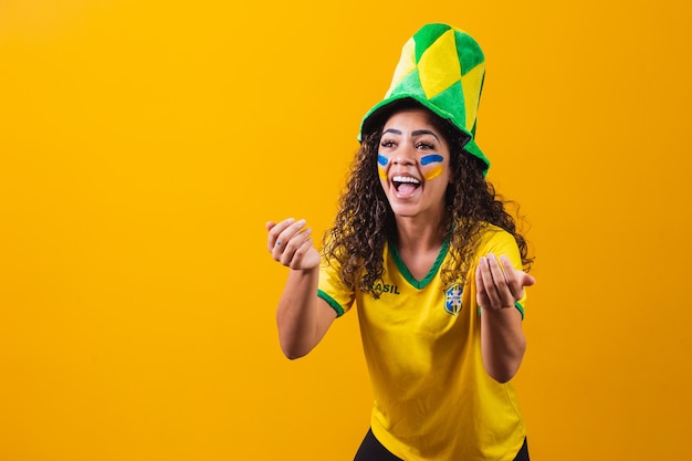 Brasilianischer Fan. mit Farbe als Make-up, brasilianischer Fan, der Fußball- oder Fußballspiel auf gelbem Hintergrund feiert. Farben Brasiliens.