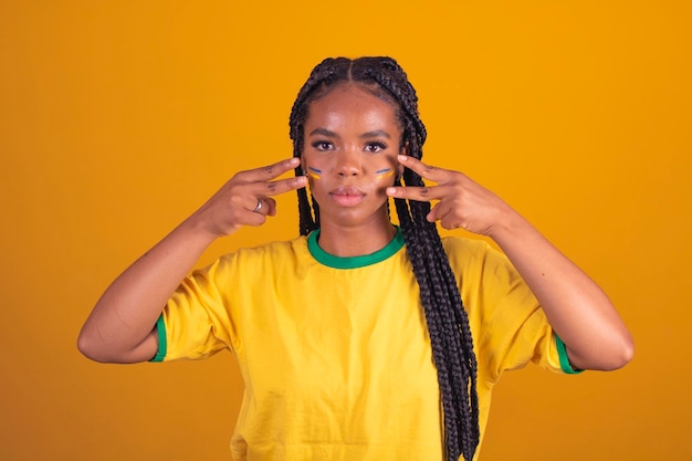 Brasilianischer Fan mit Farbe als Make-up Brasilianischer Fan feiert Fußball- oder Fußballspiel auf gelbem Hintergrund Farben Brasiliens