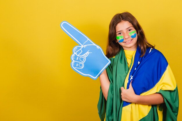 Brasilianischer kaukasischer Kinderfußballfan, der auf die Seitenwerbungswerbung zeigt Olympische Spiele der Weltmeisterschaft