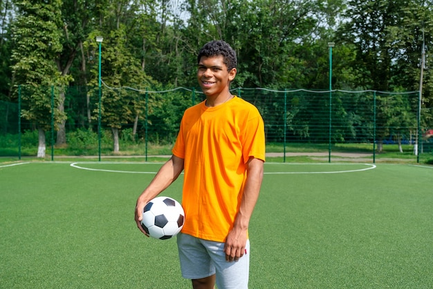 Brasilianischer Mann, der Fußball hält, während er auf dem Sportplatz steht