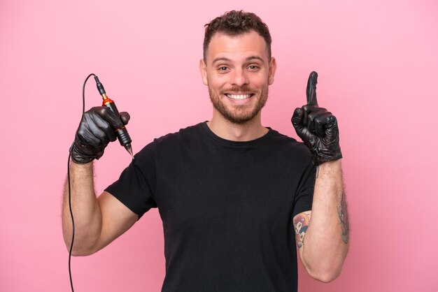 Brasilianischer Mann des Tätowierers lokalisiert auf rosa Hintergrund, der eine großartige Idee zeigt