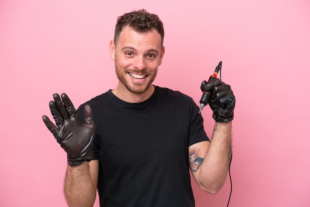 Brasilianischer Mann des Tätowierers lokalisiert auf rosa Hintergrund, der mit der Hand mit glücklichem Ausdruck salutiert