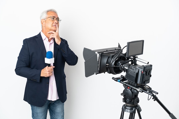 Brasilianischer Mann mittleren Alters des Reporters, der ein Mikrofon hält und Nachrichten lokalisiert auf weißem Hintergrund mit Zweifeln beim Aufblicken berichtet