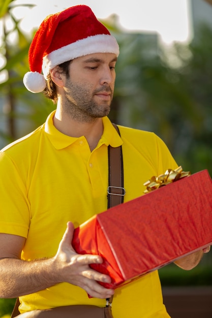 Brasilianischer Postbote verkleidet als Weihnachtsmann, der ein Geschenk liefert. Online-Kauf wird geliefert.